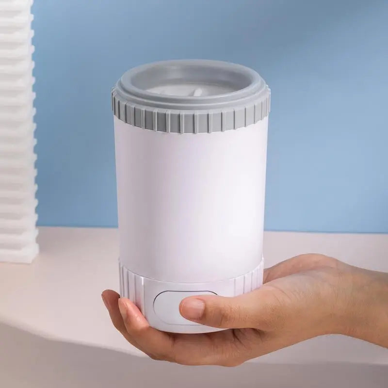 Pawssiblypets dog paw cleaner cup held in hand with white and gray compact design