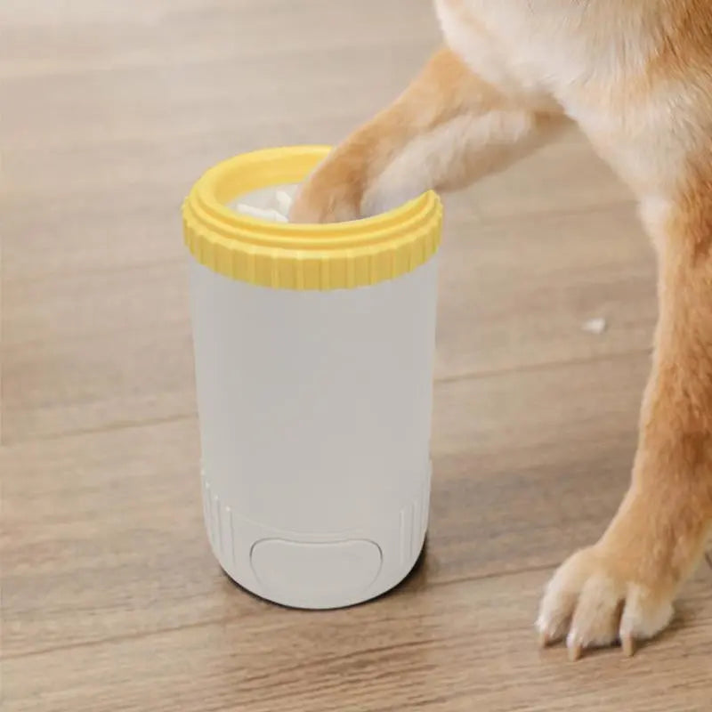 Pawssiblypets dog paw cleaner cup with yellow rim being used to clean a dog's paw on wooden floor