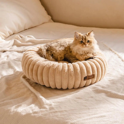 Fluffy cat resting comfortably in a beige donut cat bed by Pawssibly Pets on a soft bed